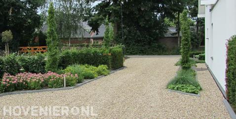 Oprit van grind met kleurrijke beplanting in border