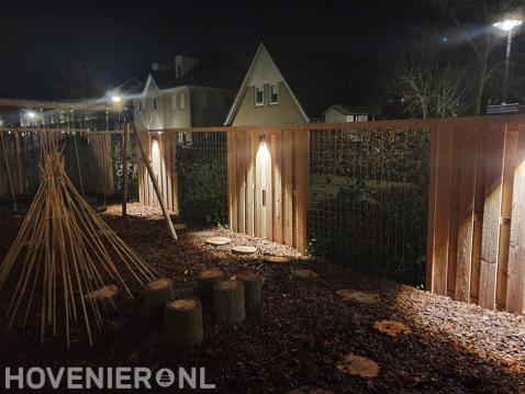 Buitenverlichting op houten schutting met betongaas schermen en klimop