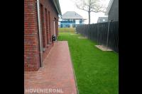 Gazon en donkere schutting langs zijkant woning