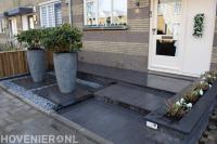 Strakke voortuin met bestrating van natuursteen en grote bloempotten