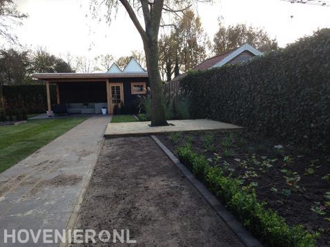 Tuinaanleg met graszoden, tuinpad en houten overkapping met berging