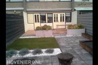 Tuinaanleg met sierbestrating, gazon, plantenbakken en vlonder
