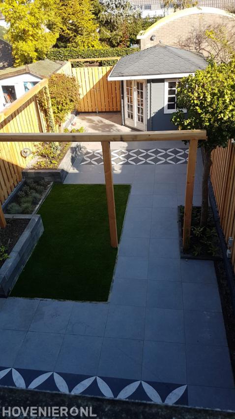 Strakke tuin met bestrating, kunstgras, verhoogde borders en pergola