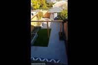 Strakke tuin met bestrating, kunstgras, verhoogde borders en pergola