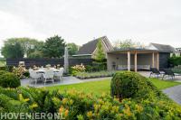 Tuinaanleg met terras, gazon en houten overkapping met schuurtje