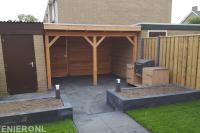 Tuinaanleg met bestrating, gazon, plantenbakken en houten overkapping