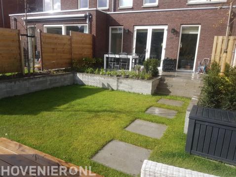 Achtertuin met verhoogd terras en gazon met stapstenen