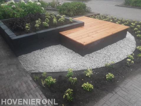 Tuinaanleg met border, grind, plantenbak en zitje van vlonderplanken