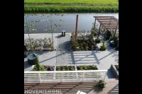 Moderne tuin aan het water met bestrating, pergola en leibomen 1