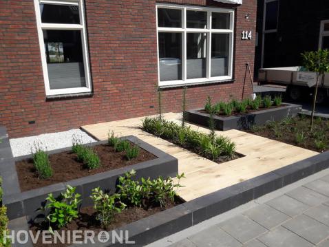 Strakke voortuin met plantenbakken en houten vlonder