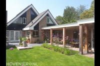 Achtertuin met gazon, terras en houten overkapping
