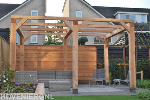 Grote houten pergola boven terras met loungeset