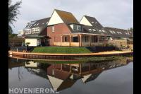 Grote houten vlonder en beschoeiing bij tuin aan het water