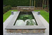 Heldere vijver met watermuur en decoratie op bodem