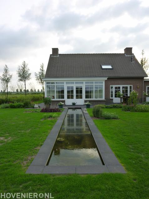 Achtertuin met strakke vijver, gazon en terras
