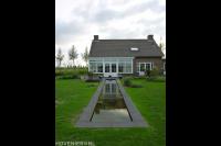 Achtertuin met strakke vijver, gazon en terras