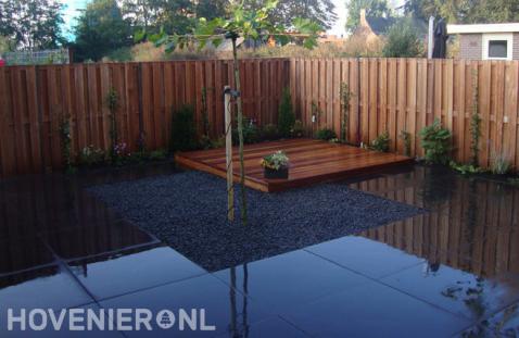 Strakke tuin met houten schutting, vlonder en grote antraciet tegels 1