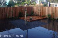 Strakke tuin met houten schutting, vlonder en grote antraciet tegels 1