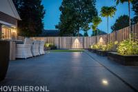 Achtertuin met sierbestrating, plantenbakken en houten schutting