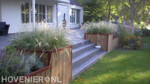 Houten bloembakken met siergras bij verhoogd terras