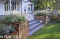 Houten bloembakken met siergras bij verhoogd terras