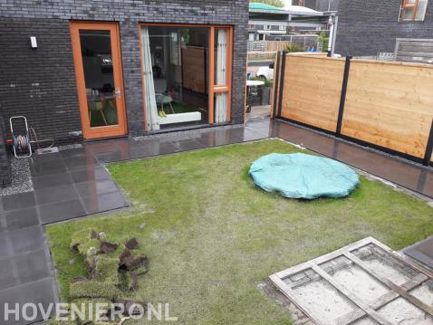 Achtertuin met bestrating, gazon en trampoline