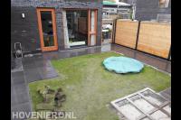 Achtertuin met bestrating, gazon en trampoline