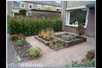 Voortuin met verhoogde borders en bestrating van waaltjes