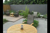 Strakke tuin met vlonder en bestrating van grijze tuintegels