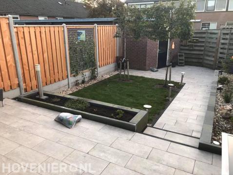 Strakke tuin met sierbestrating, gazon en verhoogd terras