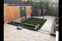 Strakke tuin met sierbestrating, gazon en verhoogd terras