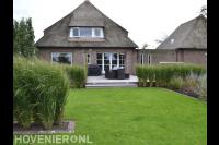 Tuin met verhoogd terras, gazon en siergras