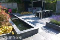 Strakke tuin met vijver en overkapping