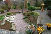 Speelse tuin met houten vlonder en pad van lichtrood split