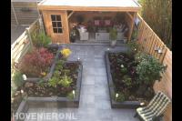 Tuin met bestrating, plantenbakken en houten overkapping met berging