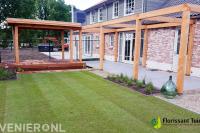 Tuin met gazon van graszoden en houten overkapping, vlonder en pergola