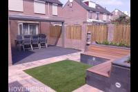 Relaxtuin met zitbank, kunstgras, schuurtje en steenschuttingen 3