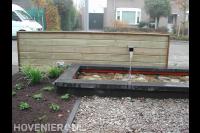 Vijver met houten watermuur en rotsblokken op bodem