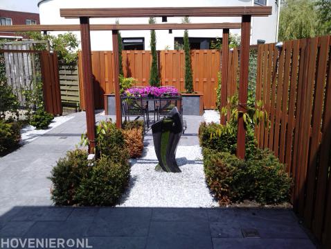 Moderne tuin met houten pergola en schutting