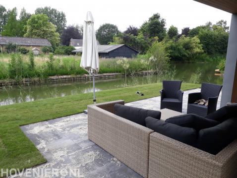 Tuin aan het water met terras en gazon