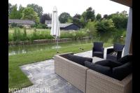Tuin aan het water met terras en gazon