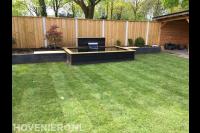 Tuinaanleg met vijver, graszoden en houten schutting