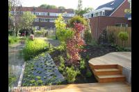 Tuin aan het water met nieuwe beplanting en houten vlonder met trap