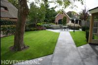 Tuin met gazon en strakke bestrating van grote antraciet tegels