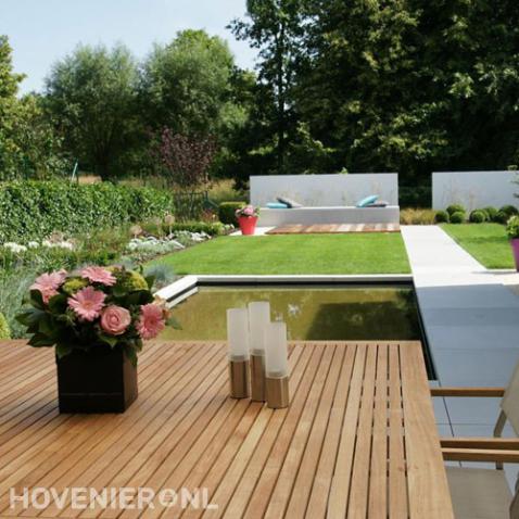 Moderne tuin met vijver, gazon en bestrating van grote tegels