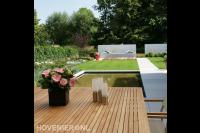 Moderne tuin met vijver, gazon en bestrating van grote tegels