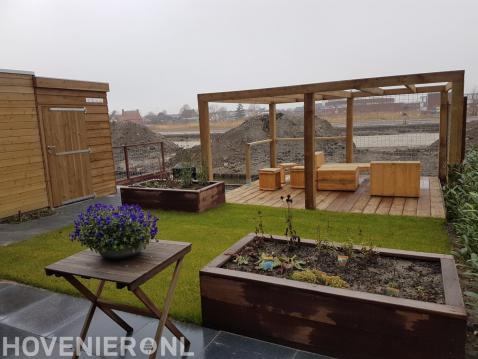 Tuin met veel houten elementen zoals pergola, vlonder en tuinmeubels