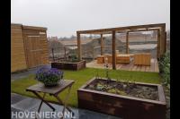 Tuin met veel houten elementen zoals pergola, vlonder en tuinmeubels