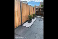 Strakke achtertuin met kiezels en beton hout schutting