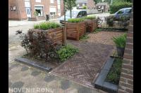 Voortuin met bestrating van waaltjes en houten bloembakken
